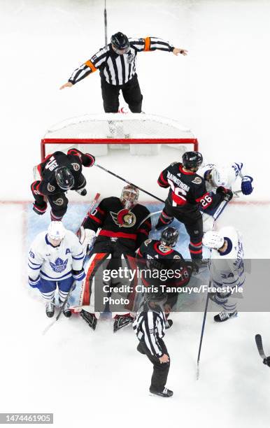 Mads Sogaard of the Ottawa Senators covers the puck amongst a scrum of his teammates Artem Zub, Erik Brannstrom, Tim Stützle, and Mitchell Marner and...