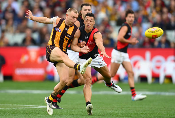 James Worpel of the Hawks kicks whilst being tackled by Dylan Shiel of the Bombers during the round one AFL match between Hawthorn Hawks and Essendon...