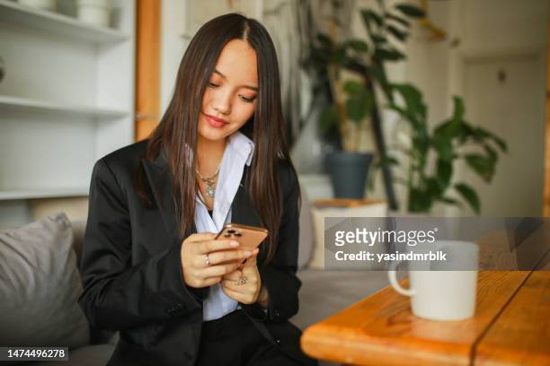 joven y hermosa mujer de negocios asiática haciendo una llamada en su teléfono móvil en un café. permite digitalizarse - asia central fotografías e imágenes de stock