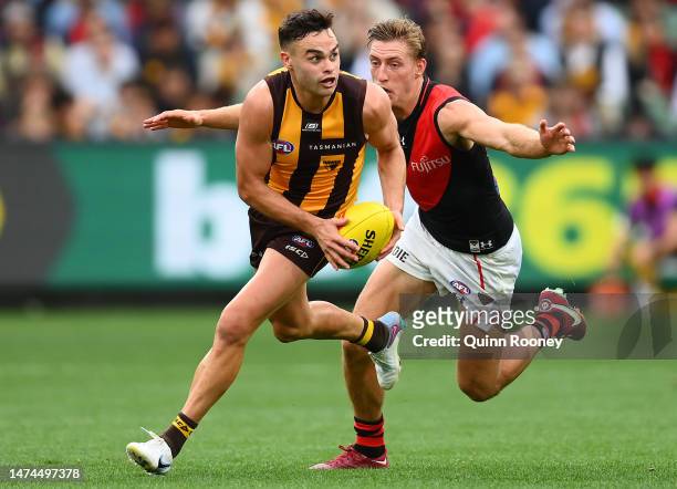 Karl Amon of the Hawks kicks whilst being tackled by Will Setterfield of the Bombers during the round one AFL match between Hawthorn Hawks and...