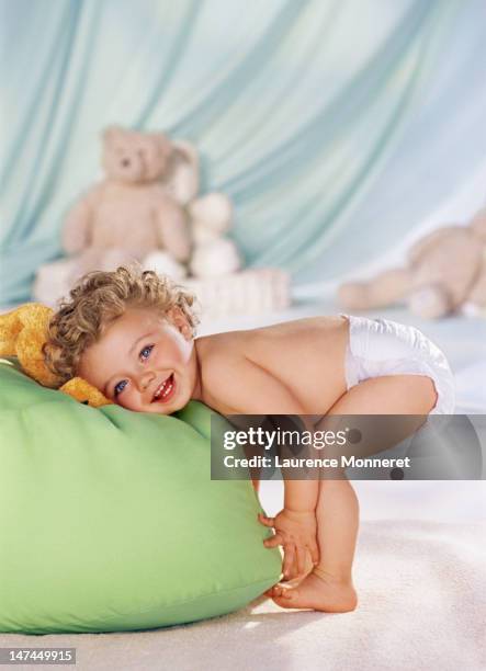 standing baby resting on a pouffe - luier stockfoto's en -beelden