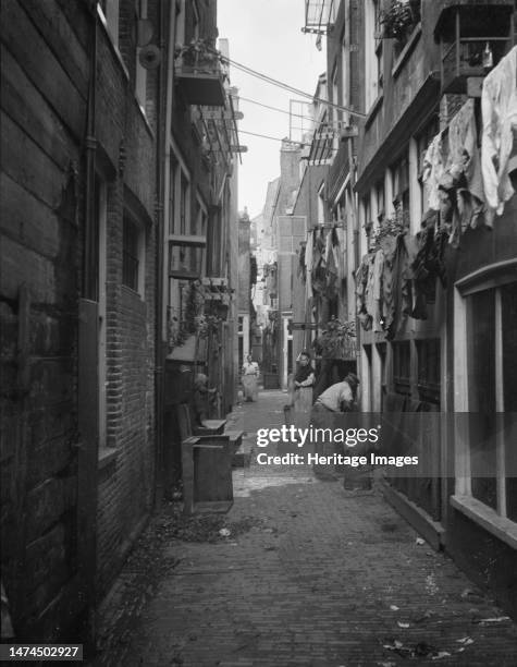 Travel views of Europe, between 1904 and 1938. Back alley with lines of washing. Note goat on upturned tub. Creator: Arnold Genthe.