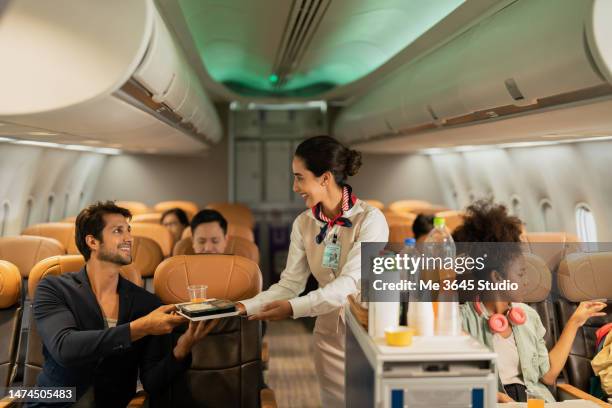 air steward takes care of passengers on the plane. - tripulación fotografías e imágenes de stock