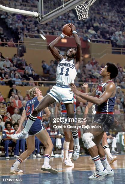 Center Bob McAdoo of the Buffalo Braves shoots the ball as forward Dick Gibbs and center Wes Unseld of the Washington Bullets look on during a...