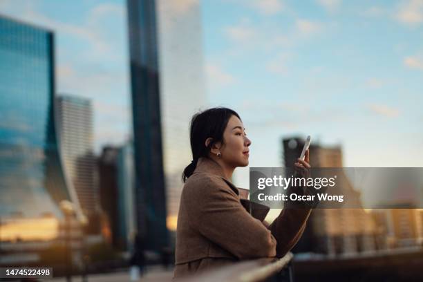 young asian business woman with smartphone in the financial district - smart city life stock pictures, royalty-free photos & images