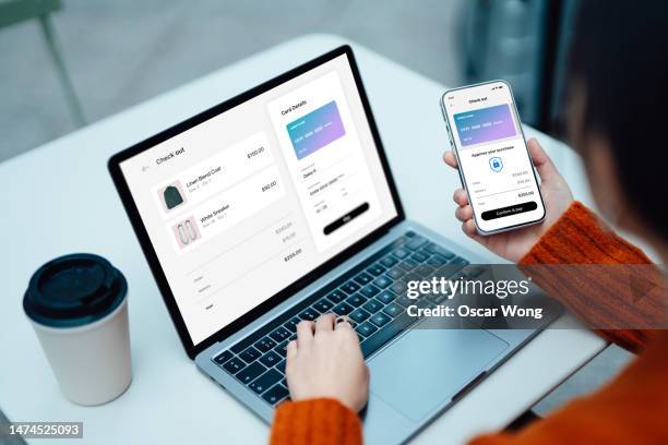 over the shoulder view of business woman making mobile payment with smartphone while doing online shopping with laptop - security code stock pictures, royalty-free photos & images