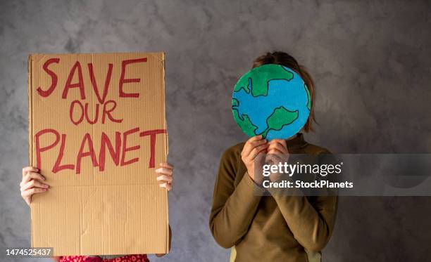 two teenage girls hold messages to save the planet. - climate protest stock pictures, royalty-free photos & images