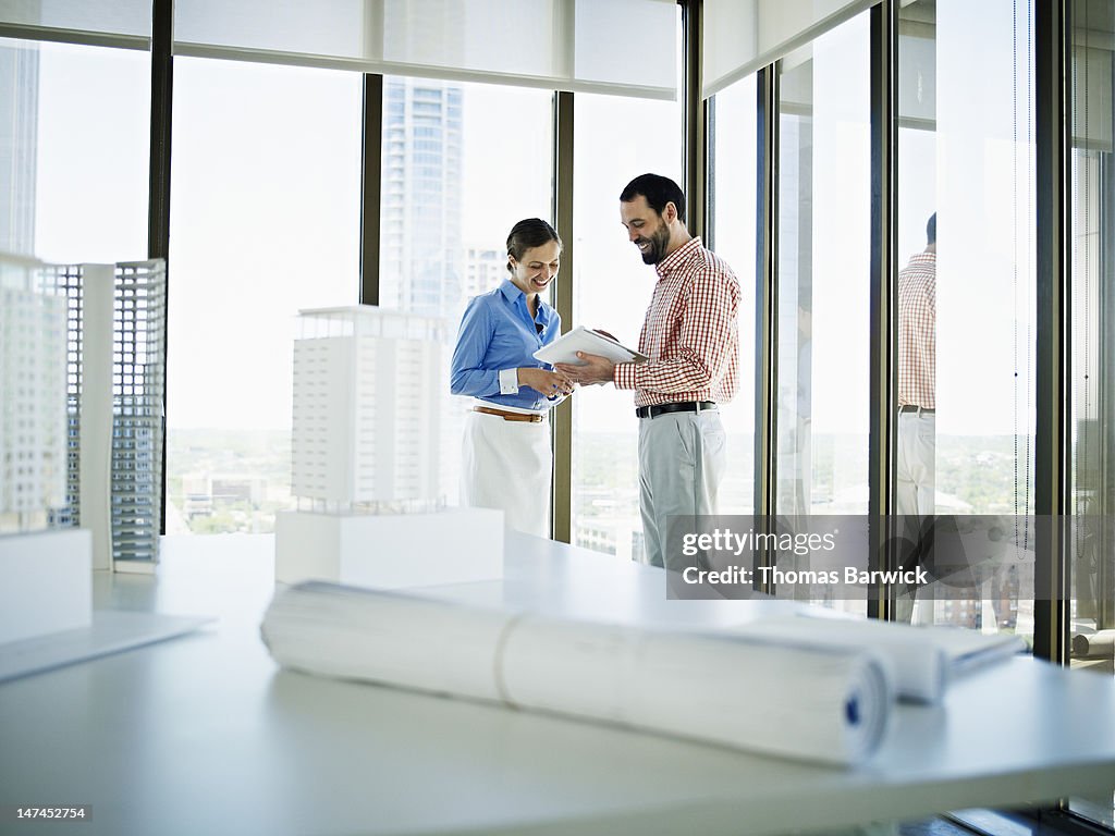 Coworkers standing in office examining documents