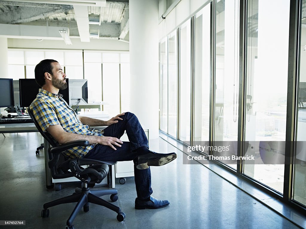 Businessman sitting at workstation looking out