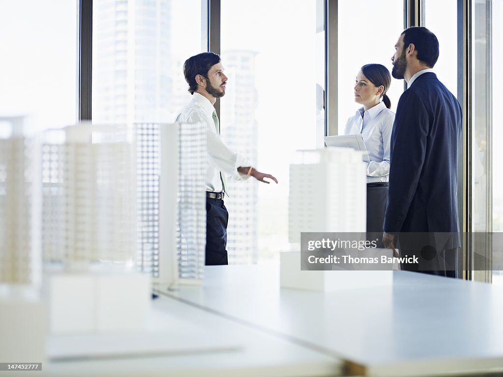 Coworkers in discussion in office near windows