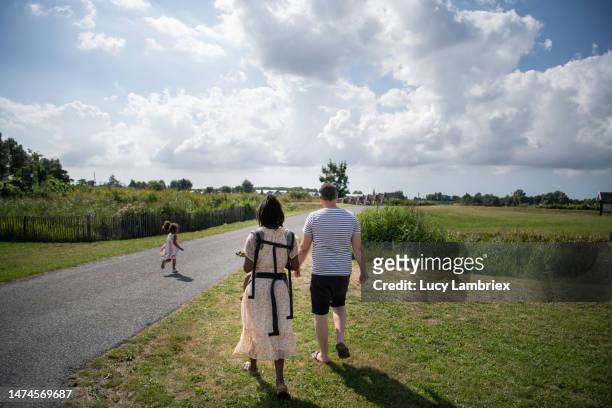 multiracial family out on a walk in the countryside, little girl running ahead - little black dress - fotografias e filmes do acervo