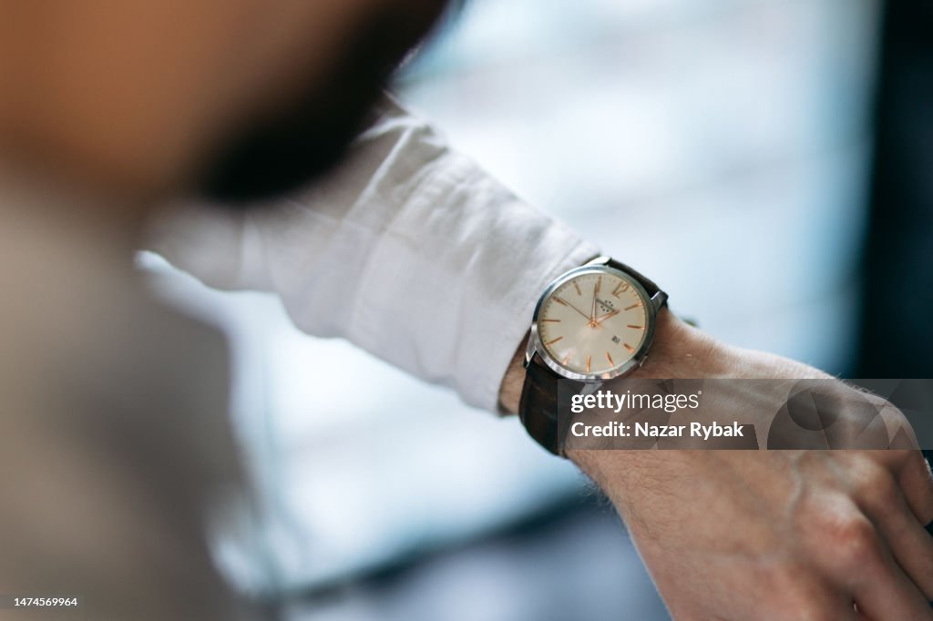 Der unkenntliche Mann, der eine Uhrzeit auf der Armbanduhr überprüft