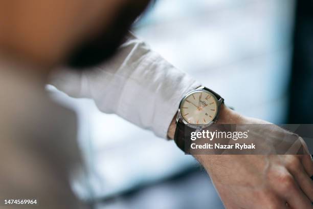 the unrecognisable man checking a time on the wristwatch - information sign stockfoto's en -beelden