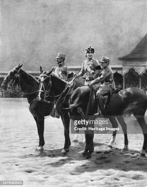 'Les souverains de Roumanie et leur second fils, le prince Nicolas assistant a une revue de troupes, a Bucarest - La reine porte l'uniforme du 4e...