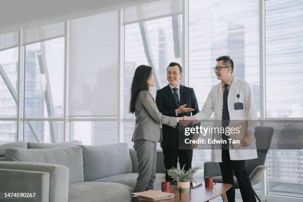 asian hospital administrator introduce medical sales representative to doctor in doctor's office business meeting - medisch vertegenwoordiger stockfoto's en -beelden