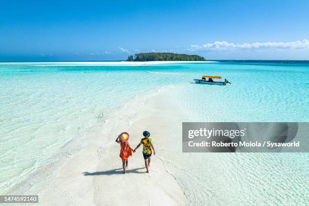 overhead view of man and woman holding hands on idyllic beach - beach holiday stock-fotos und bilder