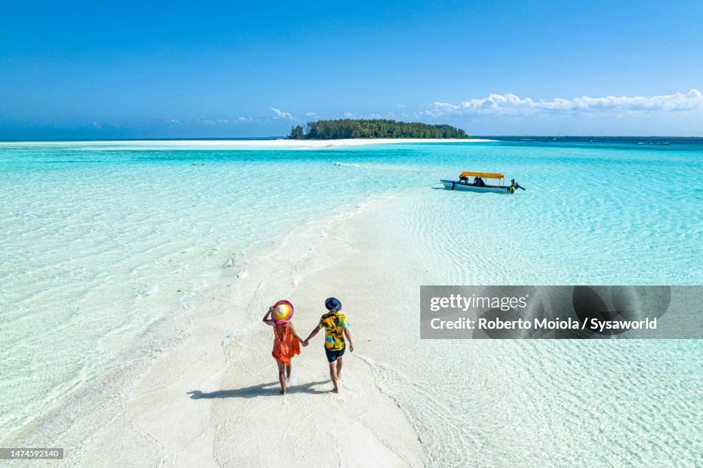 Overhead view of man and woman holding hands on idyllic beach
