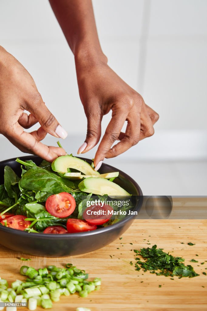 Elegant black girl preparing vegan salad in the kitchen