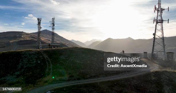 e-mountain biker rides hill below transmission tower - telecommunications tower stock pictures, royalty-free photos & images