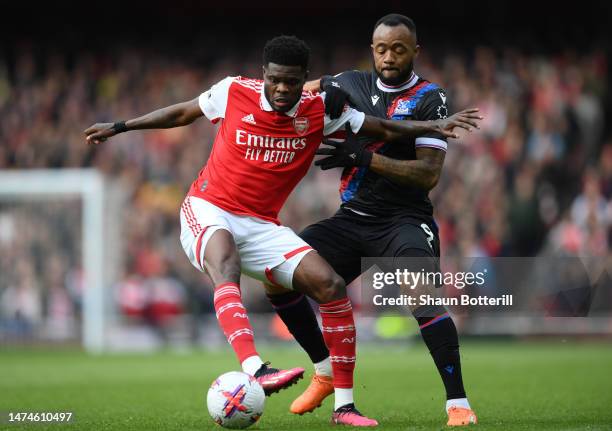 Thomas Partey of Arsenal is challenged by Jordan Ayew of Crystal Palace during the Premier League match between Arsenal FC and Crystal Palace at...