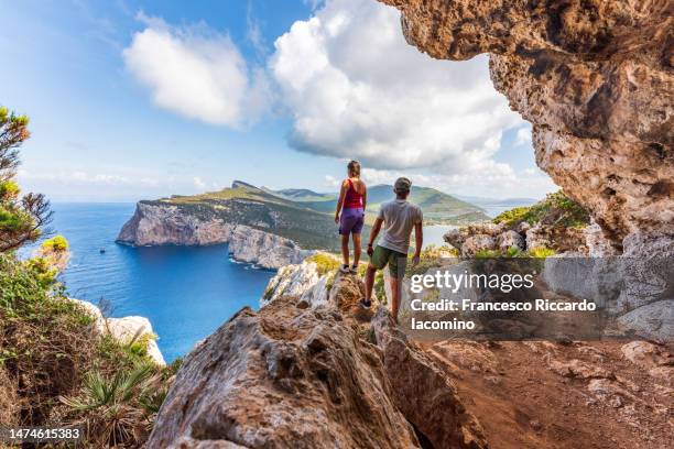 couple admiring the coastline of sardinia, italy - mezzogiorno - fotografias e filmes do acervo