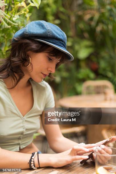 stylish woman wearing hat sitting on a table outdoors - long table stock pictures, royalty-free photos & images