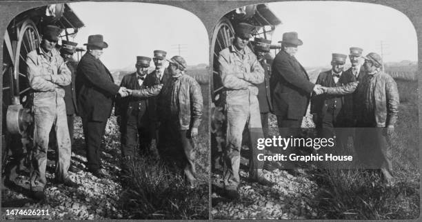 Stereoscopic image showing American politician William Howard Taft, President of the United States, shaking hands with a train engineer surrounded by...