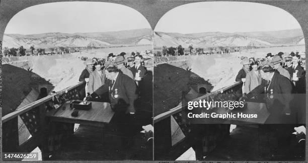 Stereoscopic image showing American politician William Howard Taft, President of the United States, touching the golden bell which opened the flood...
