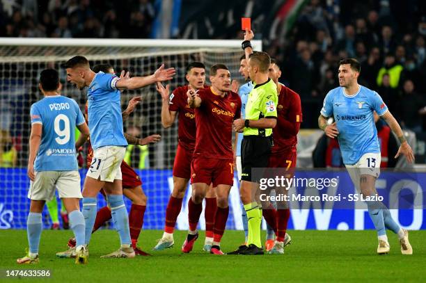 The referee Davide Massa show a red card to Roger Ibanez of AS Roma during the Serie A match between SS Lazio and AS Roma at Stadio Olimpico on March...