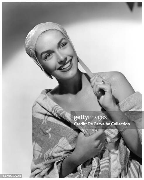 Publicity portrait of Spanish actor Jinx Falkenburg showing her dazzling smile while wet and wearing a swimming cap and wrapped in a towel, mid...