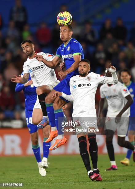 Angel Algobia of Getafe CF contends for the aerial ball with Suso and Yousseff En-Nesyri of Sevilla FC during the LaLiga Santander match between...