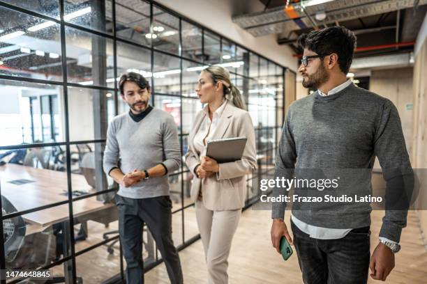 coworkers talking while walking through corridor at office - director office stock pictures, royalty-free photos & images