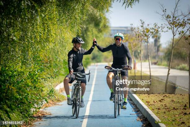 dos hombres disfrutan de un relajante paseo en bicicleta por el carril bici de la ciudad en verano - ciclista fotografías e imágenes de stock