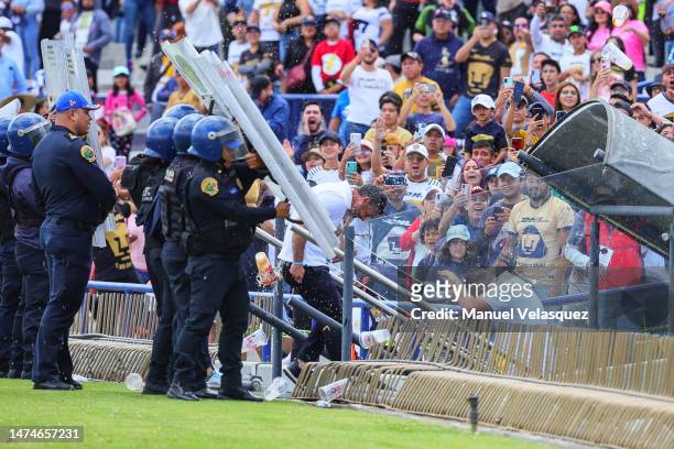 Rafael Puente head coach of Pumas leaves the pitch escorted by police officers after losing the 12th round match between Pumas UNAM and Pachuca as...