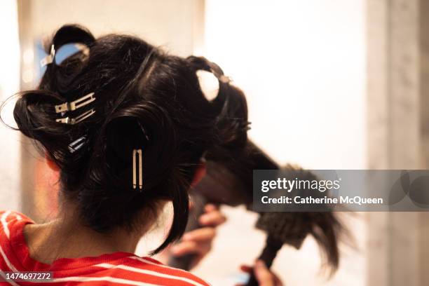 mixed-race young woman blow dries her hair at home - black hair salon stock pictures, royalty-free photos & images