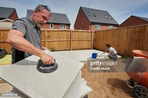 landscapers laying porcelain patio tiles - tradie stock pictures, royalty-free photos & images