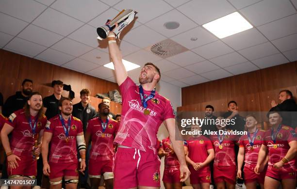 Ollie Devoto of Exeter Chiefs celebrates with the Premiership Rugby Cup as players of Exeter Chiefs celebrate in the changing room after defeating...