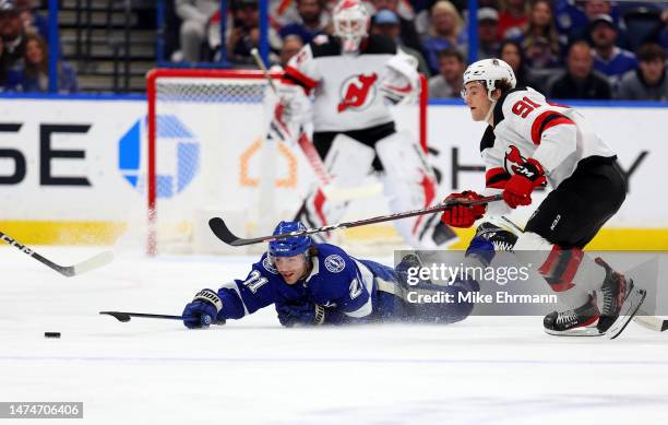 Brayden Point of the Tampa Bay Lightning and Dawson Mercer of the New Jersey Devils fight for the puck during a game at Amalie Arena on March 19,...