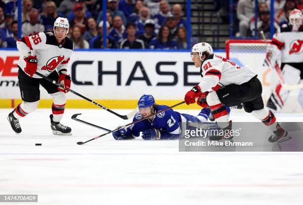 Brayden Point of the Tampa Bay Lightning and Dawson Mercer of the New Jersey Devils fight for the puck during a game at Amalie Arena on March 19,...