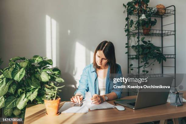 top view close up woman calculating bills, money, loan or rent payments, using laptop, online banking service, sitting at table, female holding receipt, planning budget, managing expenses, finances - fiscalité photos et images de collection