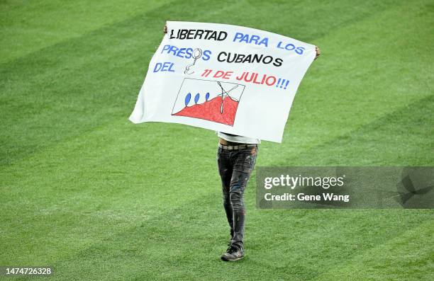 Protestor runs on to the field at loanDepot park and waving flag during the World Baseball Classic Semifinals between Cuba and United States at...