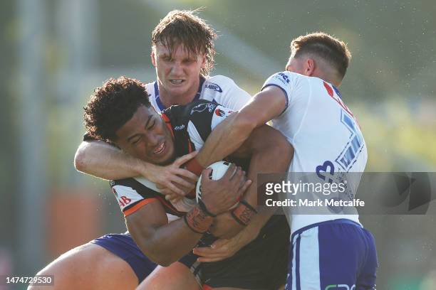 Junior Tupou of the Wests Tigers is tackled during the round three NRL match between Canterbury Bulldogs and Wests Tigers at Belmore Sports Ground on...