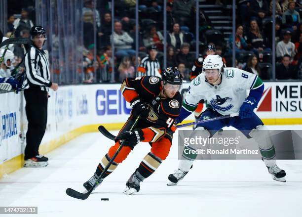 Cam Fowler of the Anaheim Ducks skates the puck against Brock Boeser of the Vancouver Canucks in the third period at Honda Center on March 19, 2023...