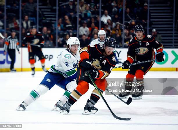 Cam Fowler of the Anaheim Ducks skates the puck against Brock Boeser of the Vancouver Canucks in the third period at Honda Center on March 19, 2023...
