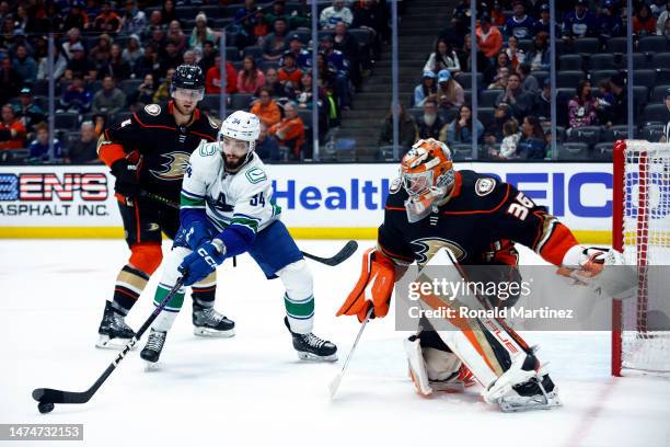 Phillip Di Giuseppe of the Vancouver Canucks skates the puck against John Gibson of the Anaheim Ducks in the third period at Honda Center on March...