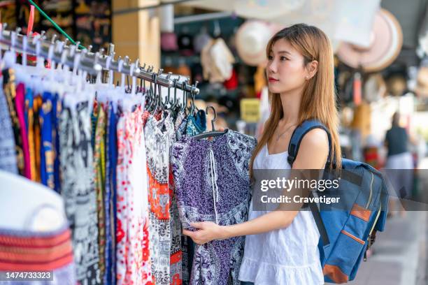 asian traveler shopping in the traditional market and thinking what to buy for souvenirs cloth in market street in bangkok, thailand. - pop up store stock pictures, royalty-free photos & images