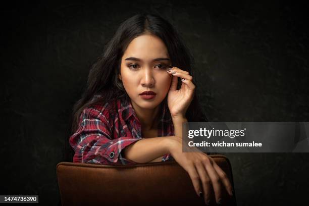 asian woman sitting in chair facing sideways - thai ethnicity stock pictures, royalty-free photos & images