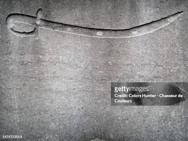 a saber engraved in the weathered gray stone stele of the tomb of a former napoleonic soldier (18th century) at the pere lachaise cemetery in paris, france - dagger isolated stock pictures, royalty-free photos & images
