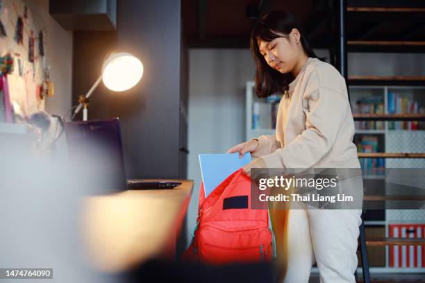 young asian girl packing for school - packing kids backpack stockfoto's en -beelden