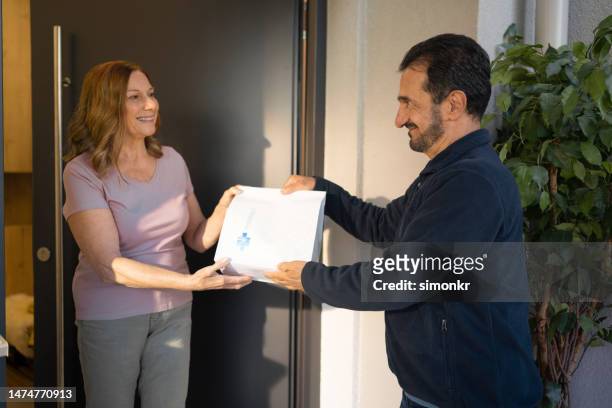 delivery person delivering medicine to woman - prescription home delivery stock pictures, royalty-free photos & images